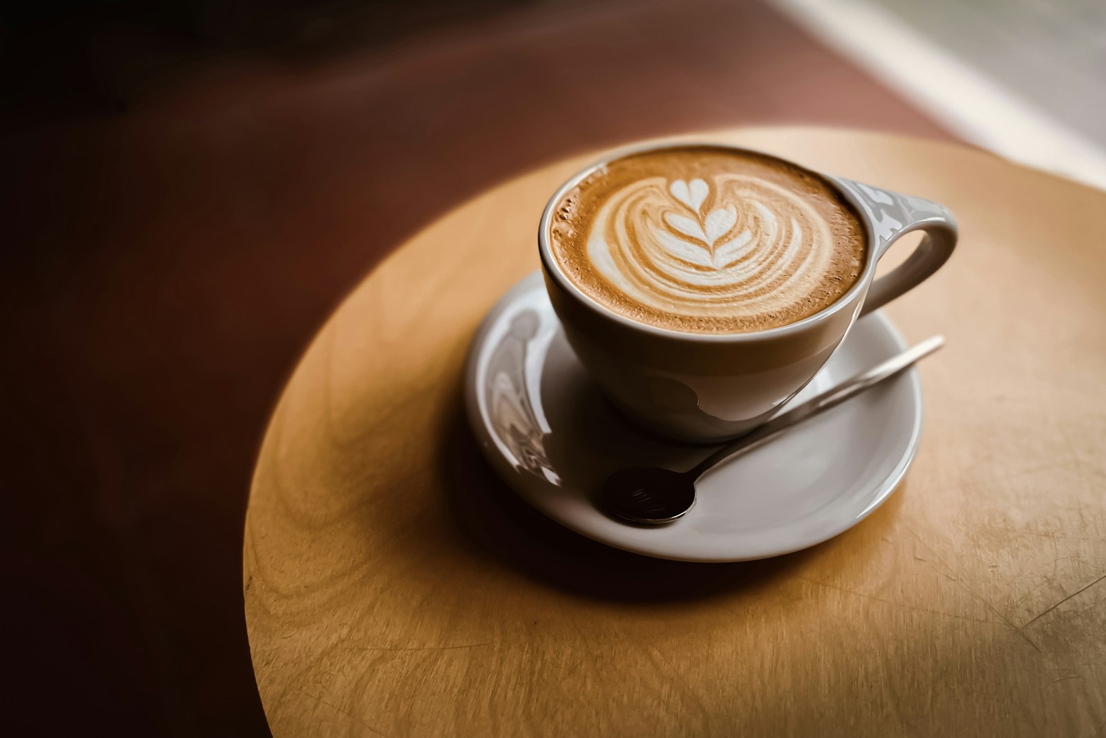 A latte with a heart design in latte art, sitting on a wooden table